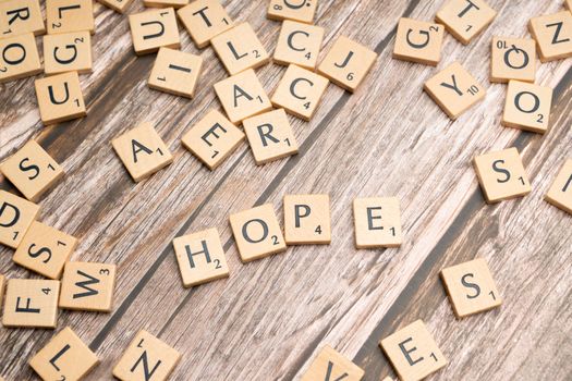 Scrabble tiles spelling 'hope' on a rustic wooden background, symbolizing inspiration.