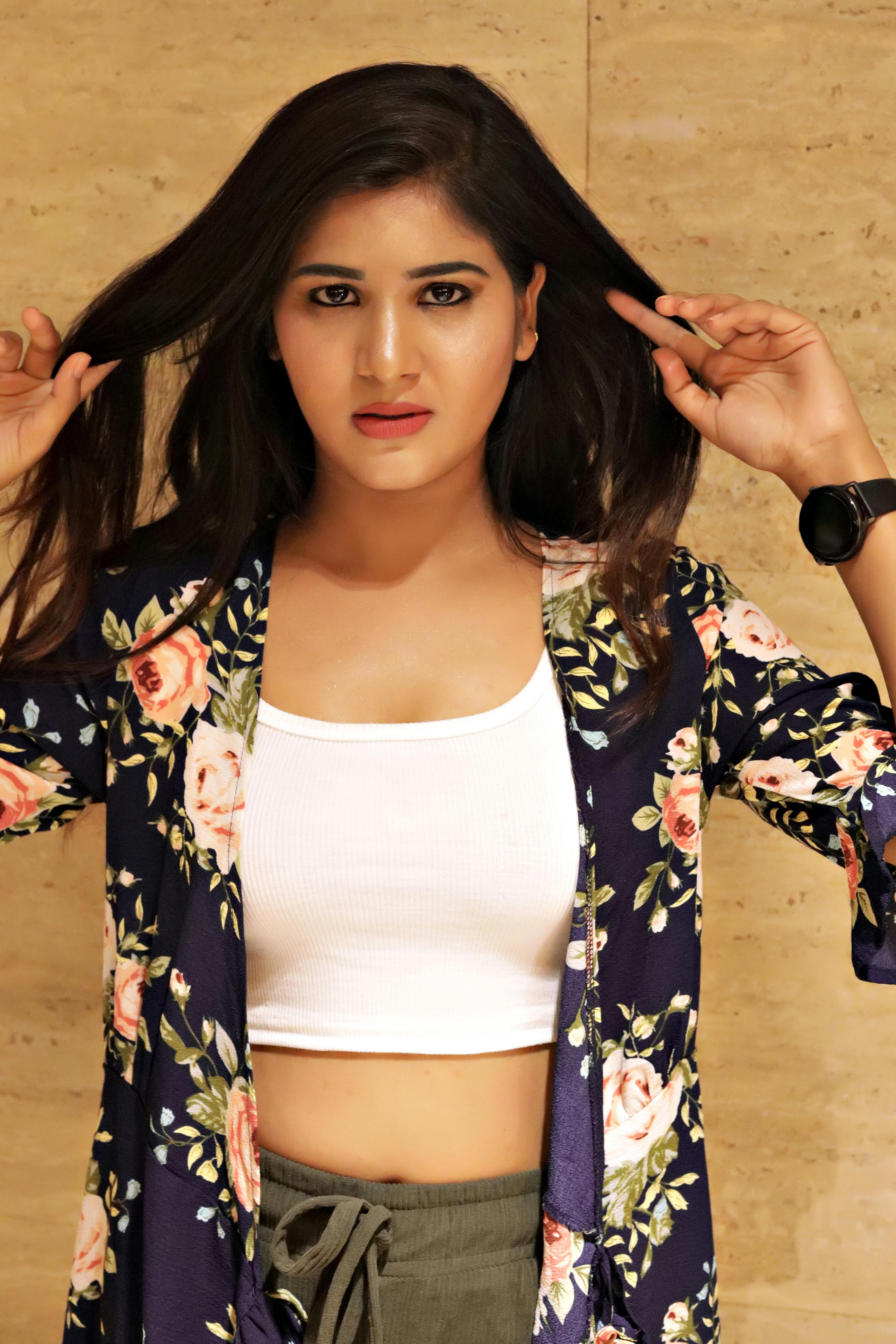 Stylish woman in floral attire posing indoors with confident expression.