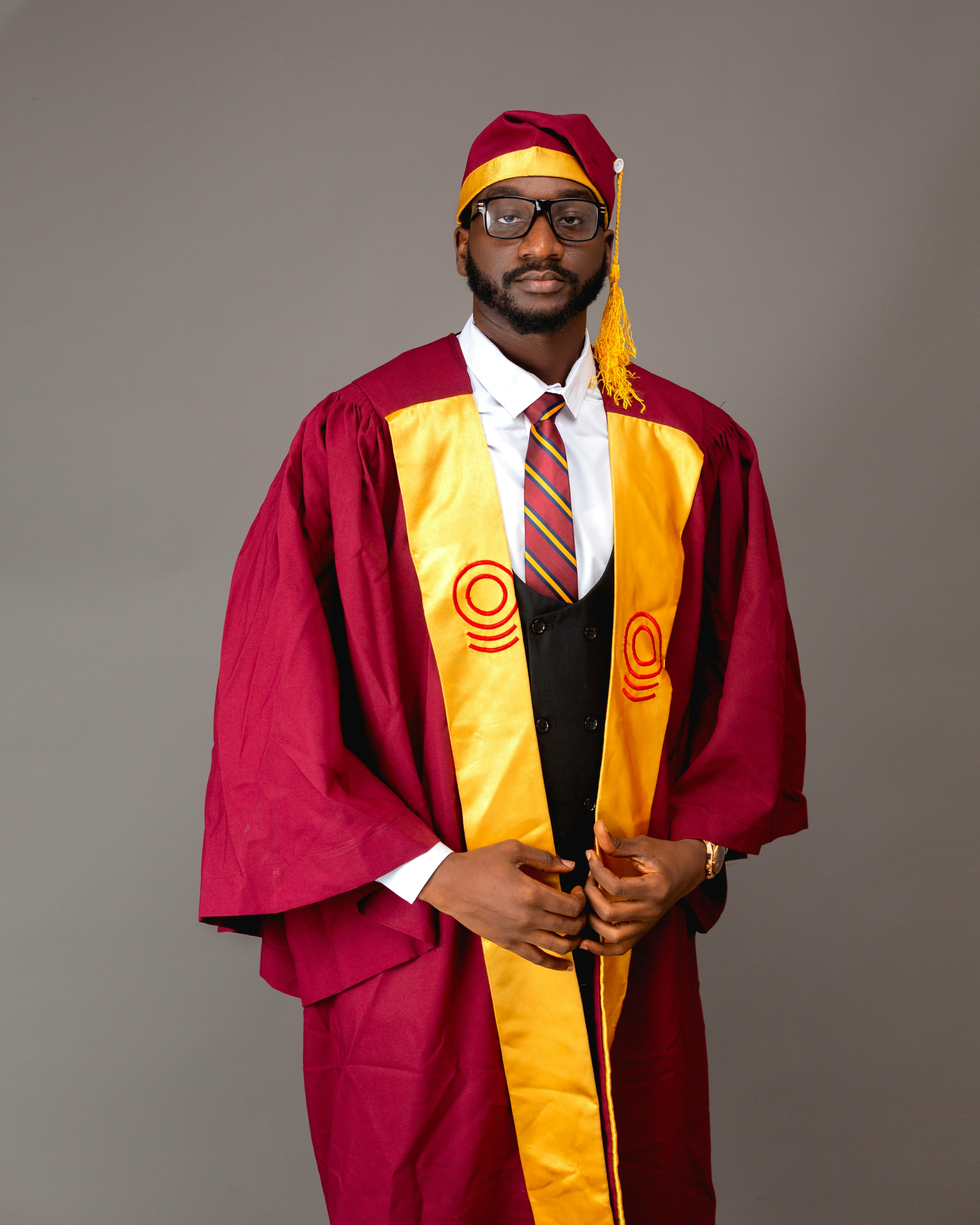 Elegant portrait of a graduate in cap and gown on a gray background.