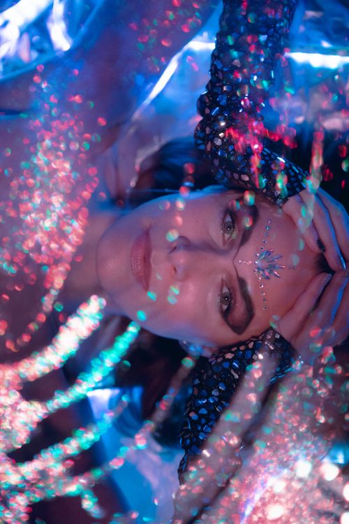 Free Close-up of a woman with artistic makeup, beads, and glowing glitter. Stock Photo