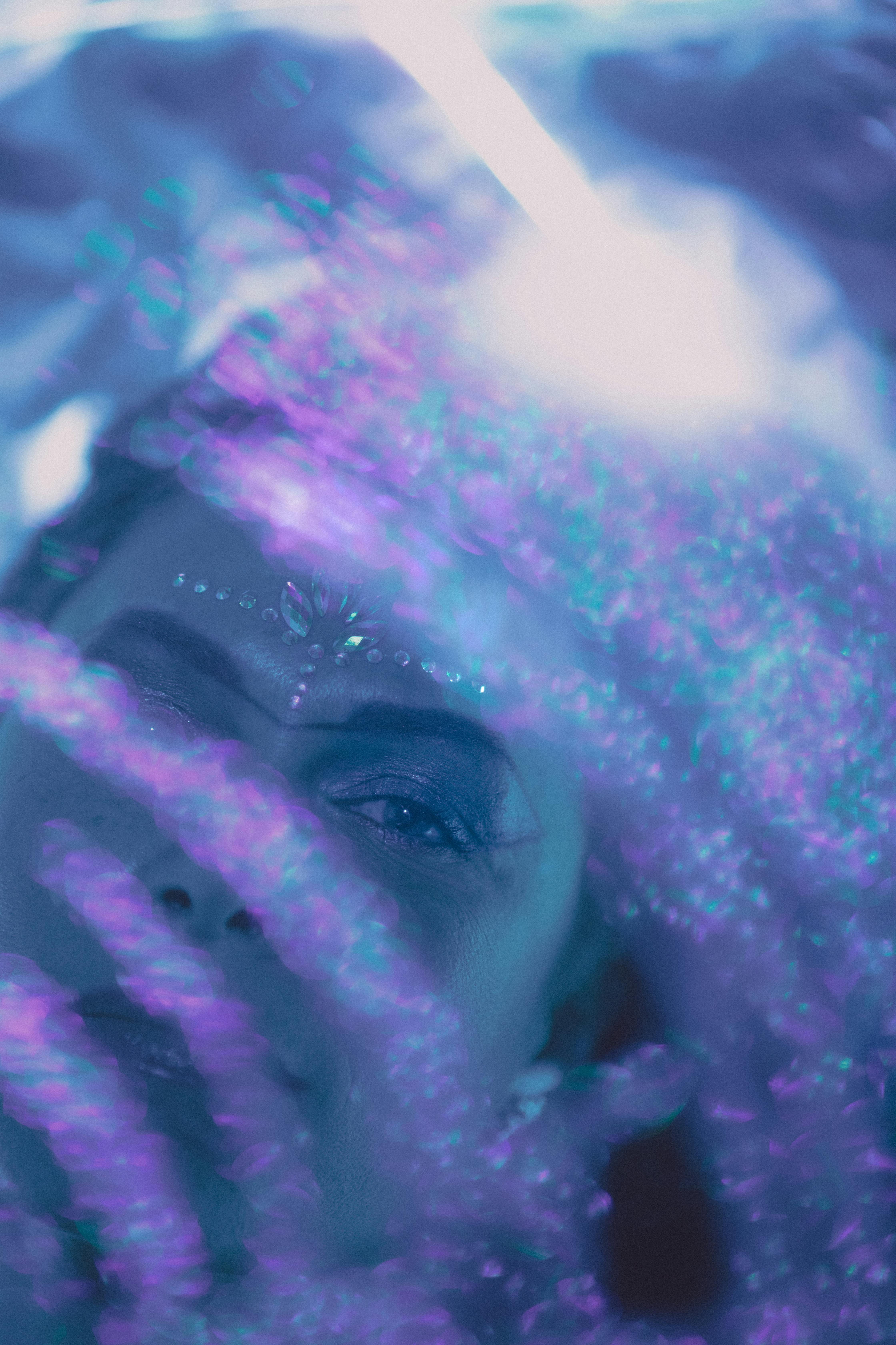 A mesmerizing portrait featuring a woman's face with glowing glitter and ethereal reflections.