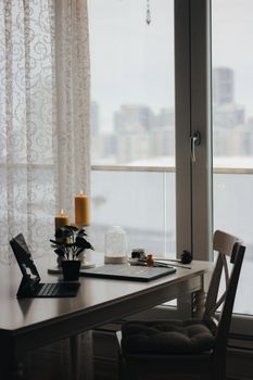 A serene indoor workspace is adorned with candles and a view of the city through a window.