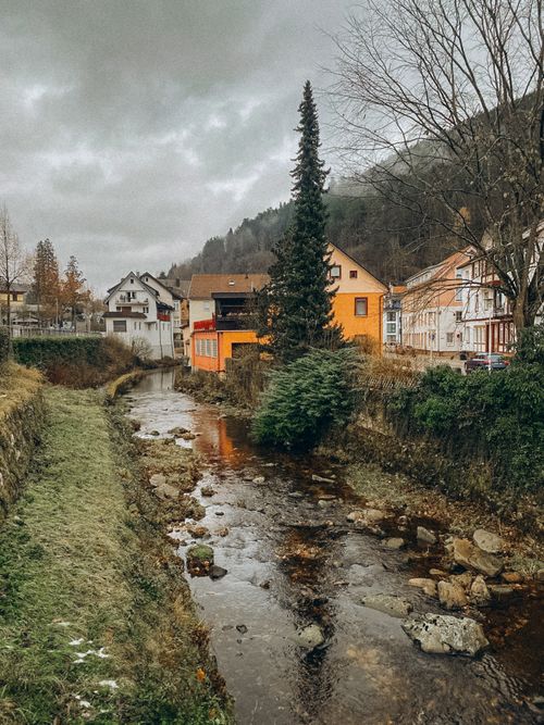 Free Quaint town scene with colorful houses by a serene river, nestled in autumn landscapes. Stock Photo