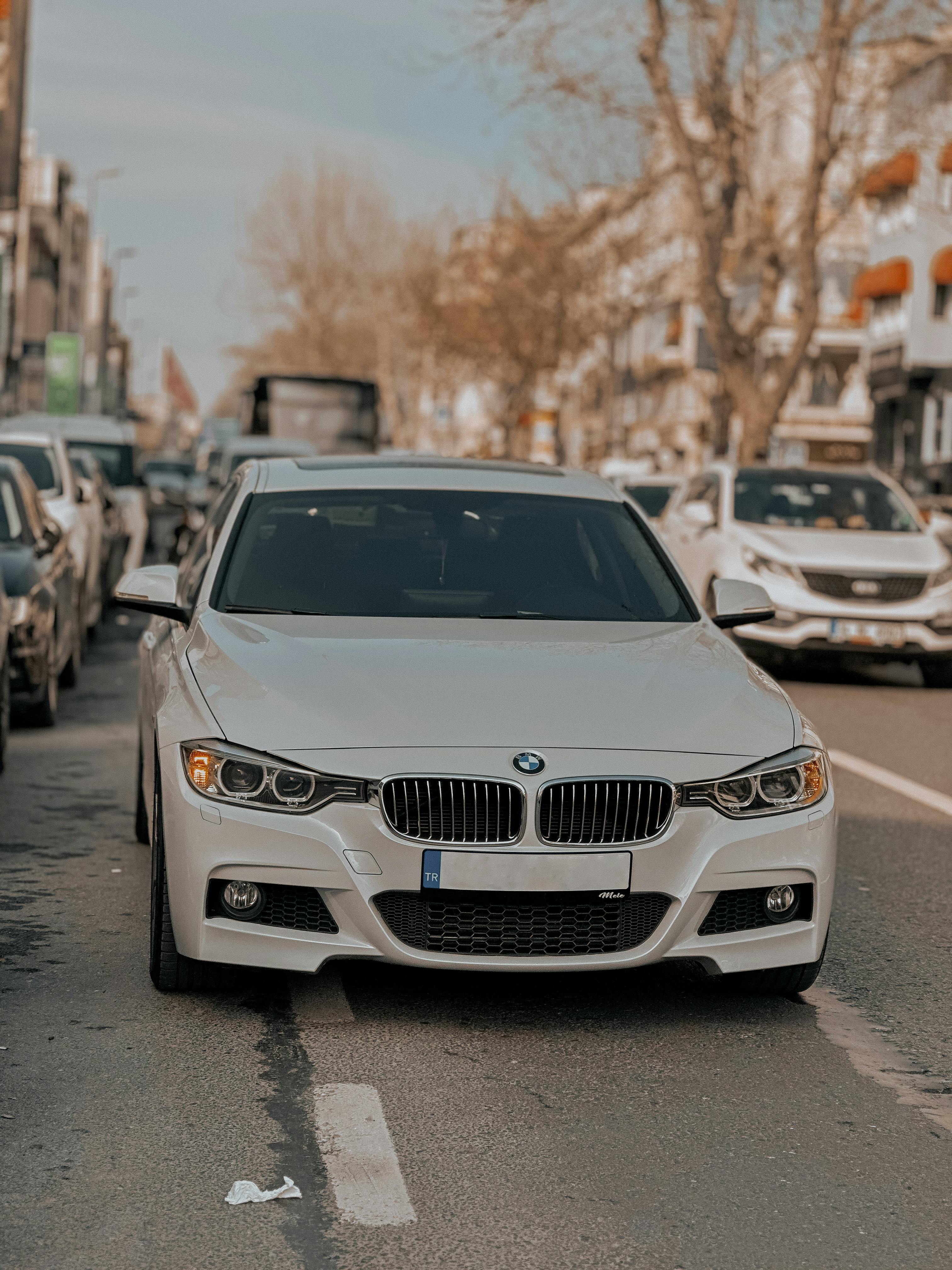 White BMW sports car parked on a bustling urban city street during daytime.