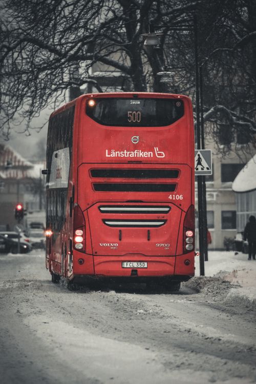 Free Red bus navigating snowy streets in Jönköping, Sweden during winter. Stock Photo