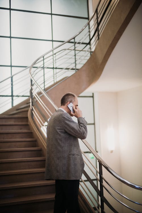 Free Man Listening to Smartphone While Standing on Staircase Stock Photo