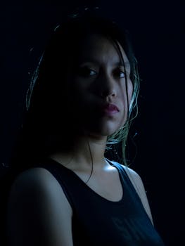 Dramatic moody portrait of a woman with long hair on a dark background.