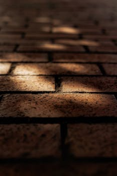 Close-up of red brick pavement with shadows creating a moody atmosphere.