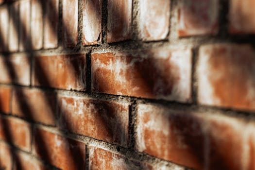 Close-up of a sunlit brick wall casting shadows, showcasing urban textures.