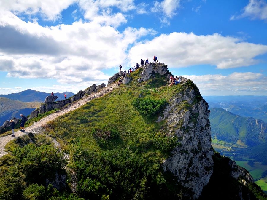 Skupina turistů na skalnatém vrcholu v Malé Fatře s výhledem do údolí