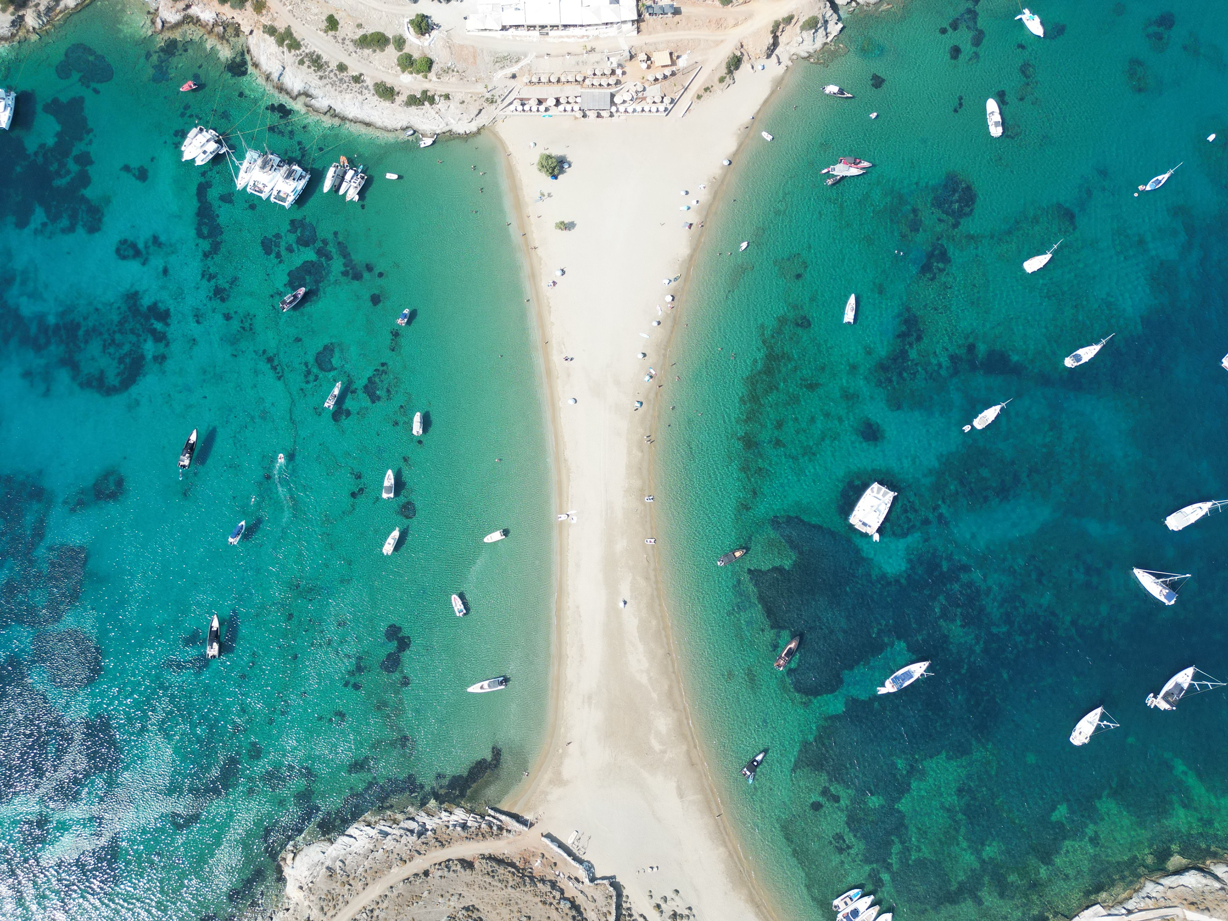 A stunning aerial view of Kythnos, Greece, showcasing a sandy beach, turquoise waters, and anchored boats.