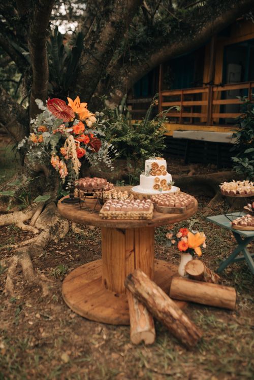 Free A rustic outdoor scene featuring cakes and vibrant floral arrangements on a wooden table. Stock Photo