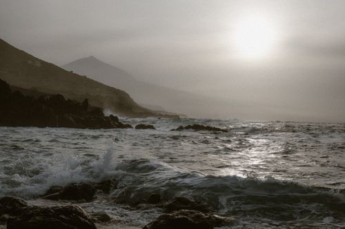 Free A tranquil seascape with waves crashing on rocky shores, illuminated by soft sunlight. Stock Photo