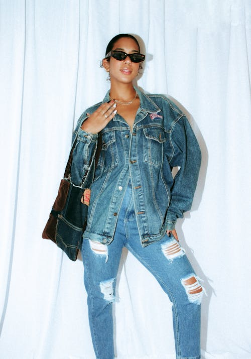 A woman in a denim jacket and ripped jeans