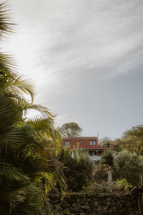 Free A picturesque rural house nestled amidst trees and lush greenery under a serene sky. Stock Photo
