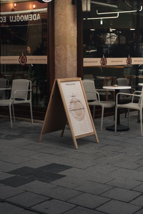 Free Cozy urban café with outdoor seating and menu board, creating a welcoming atmosphere in the city. Stock Photo