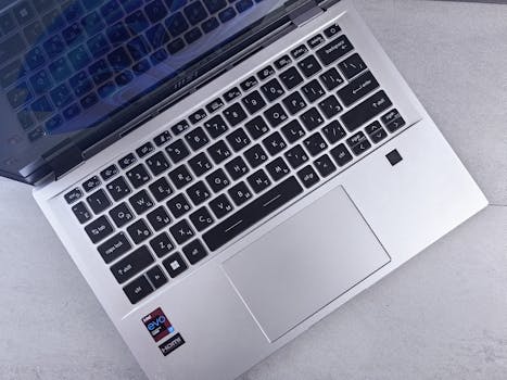 Top view of a sleek silver laptop with a backlit keyboard on a minimalist desk surface.