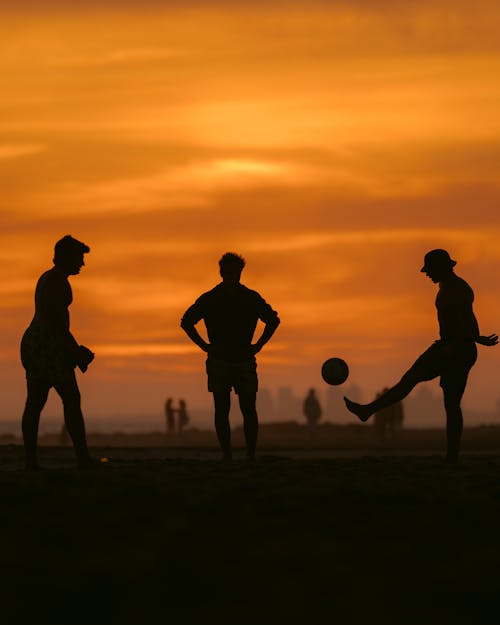 Silhouette of Men Playing Soccer on Beach