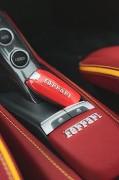 Close-up of red Ferrari car interior featuring luxury leather seats and branded key. Captured in Kraków, Poland.