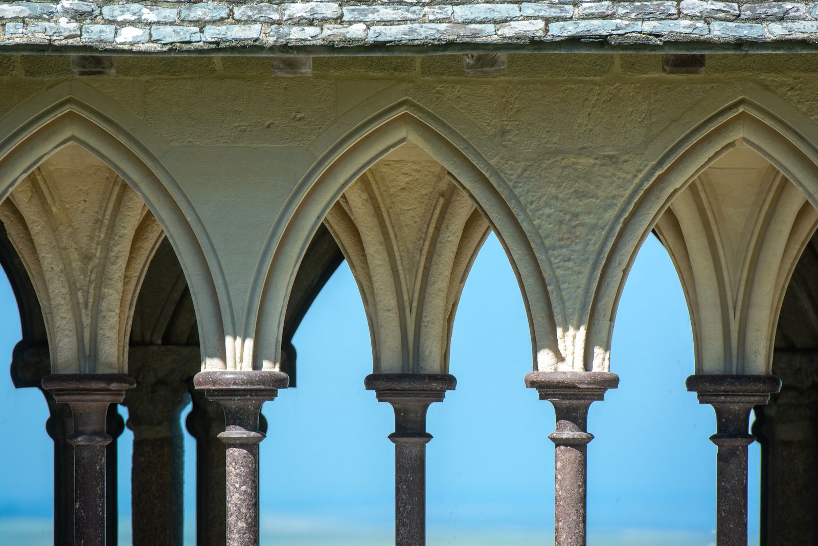 Cloître d'abbaye occitane au lever du soleil, lumière dorée sur la pierre, ambiance contemplative