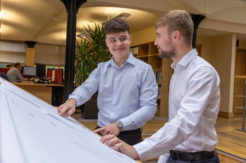 Young Men Looking at a Whiteboard and Holding a Discussion 