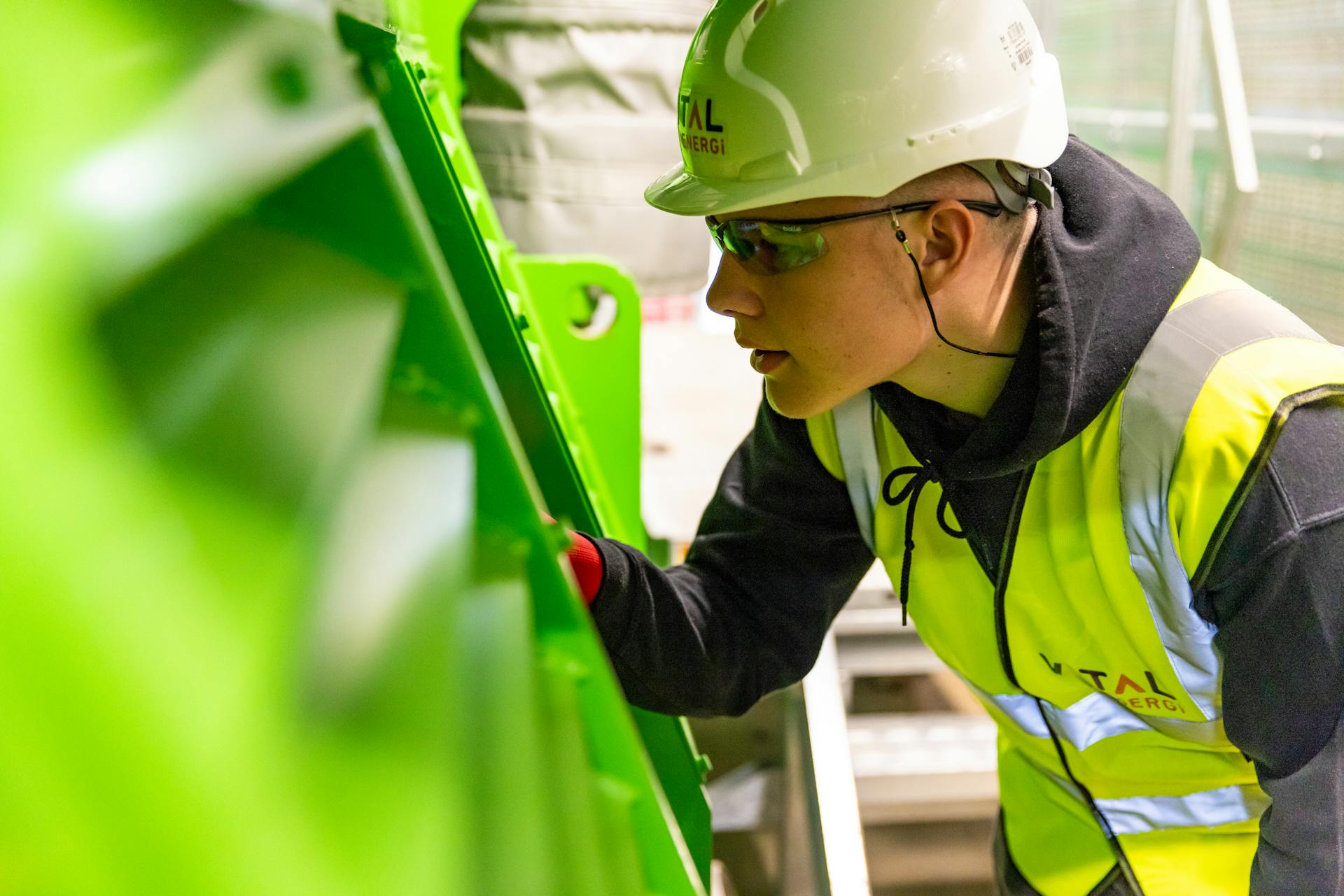 Safety-conscious factory worker inspects machinery for quality control in industrial setting.