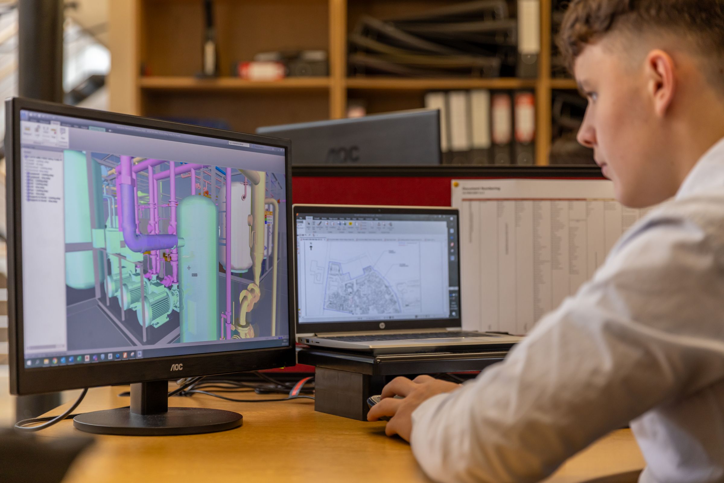 Engineer working with CATIA V5 CAD software on dual monitors