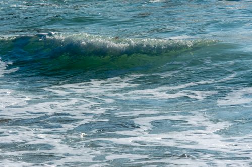 Free Vibrant ocean waves with foam gently crash on the coastal shores, capturing natural beauty. Stock Photo