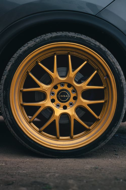 Free Detailed view of a stylish golden rim on a Nissan vehicle, showcasing automotive design. Stock Photo