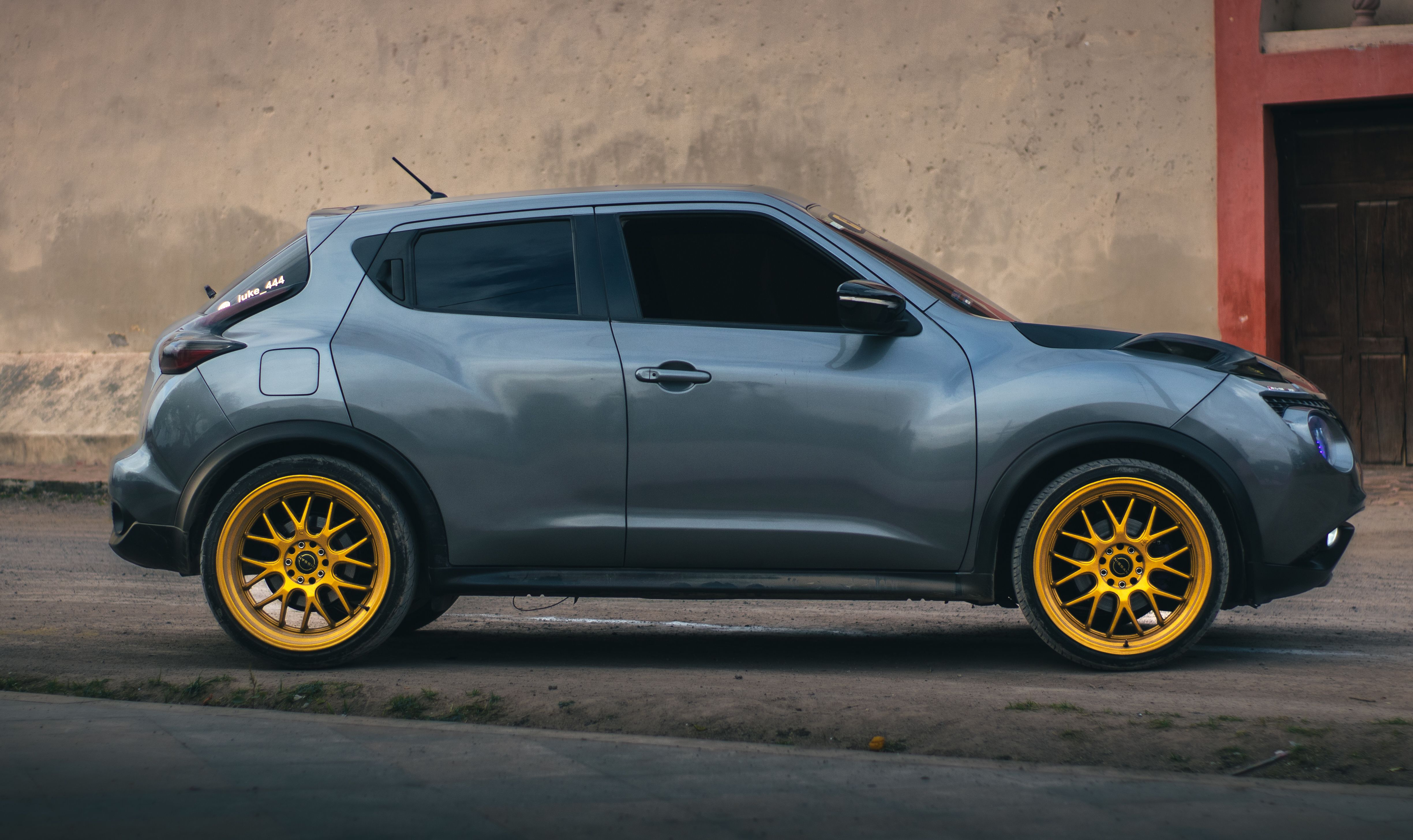 Side profile of a modern gray SUV with striking yellow alloy wheels in an urban setting.