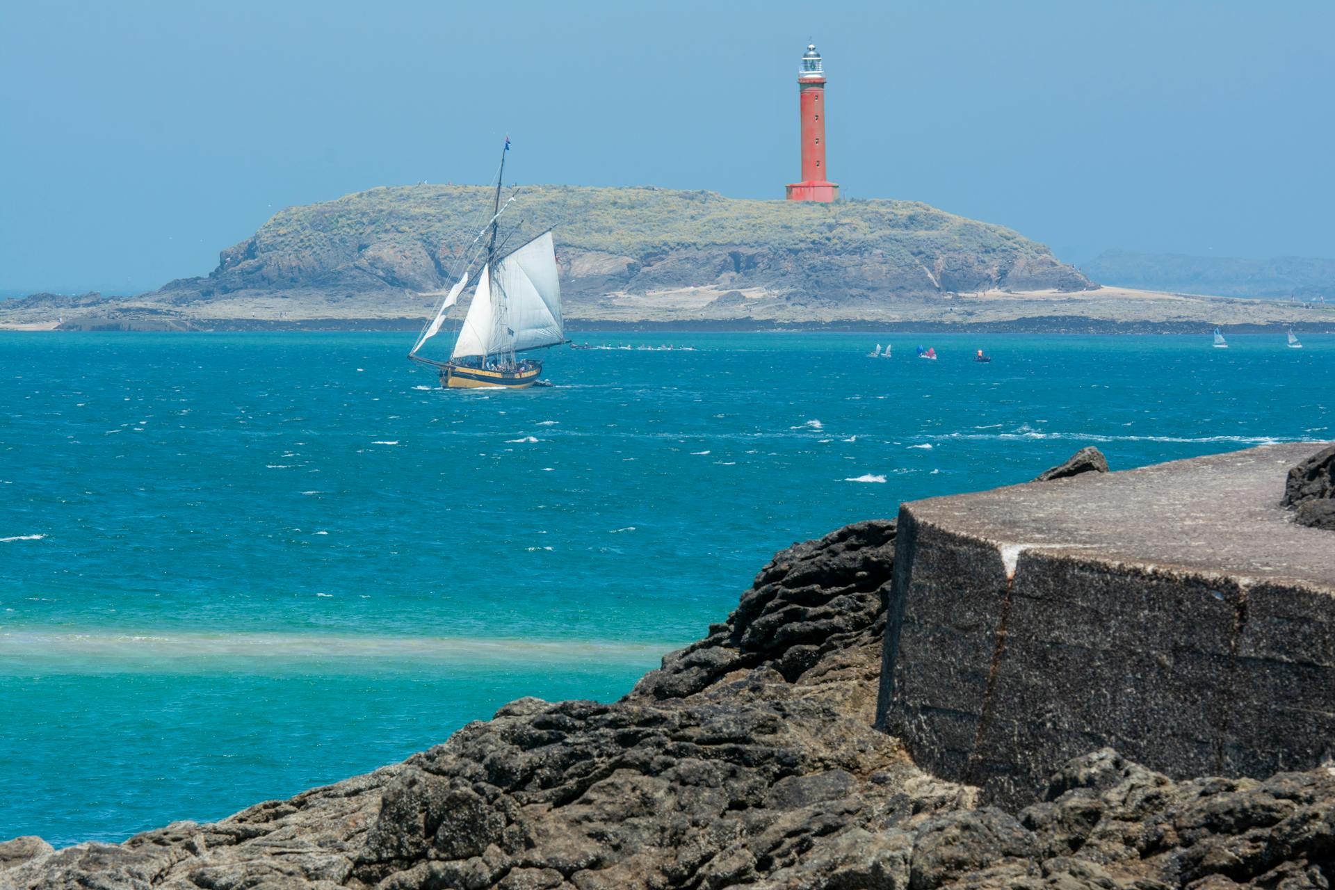 Replica of the French Renard Cutter Sailing Next to the Lighthouse