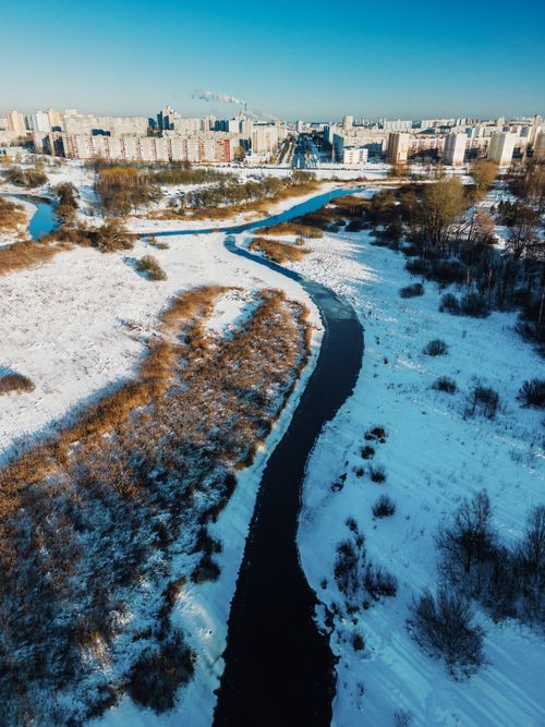 Free A scenic aerial view of Minsk under a blanket of snow, featuring a winding river and urban landscape. Stock Photo