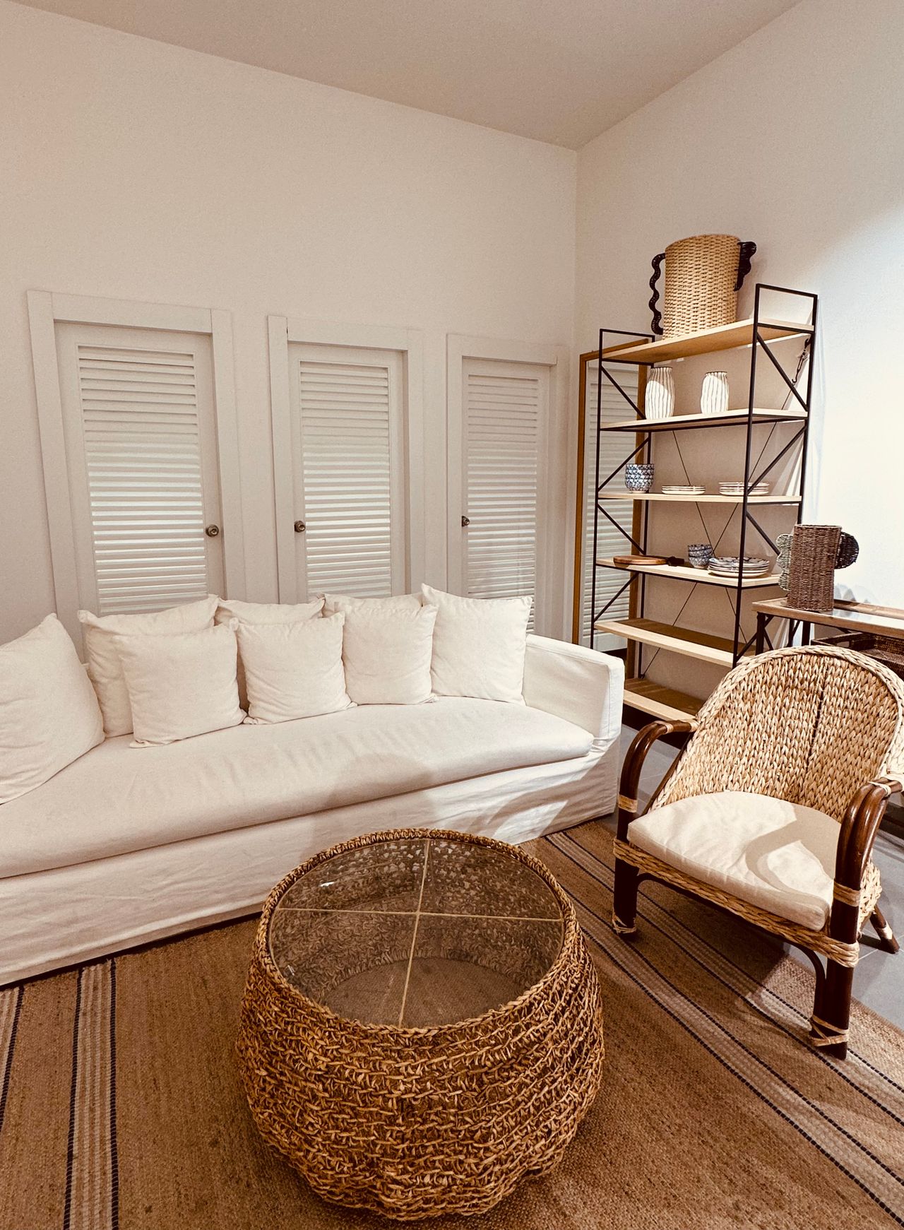 White slipcovered sofa with woven rattan coffee table and chair in a bright coastal living room