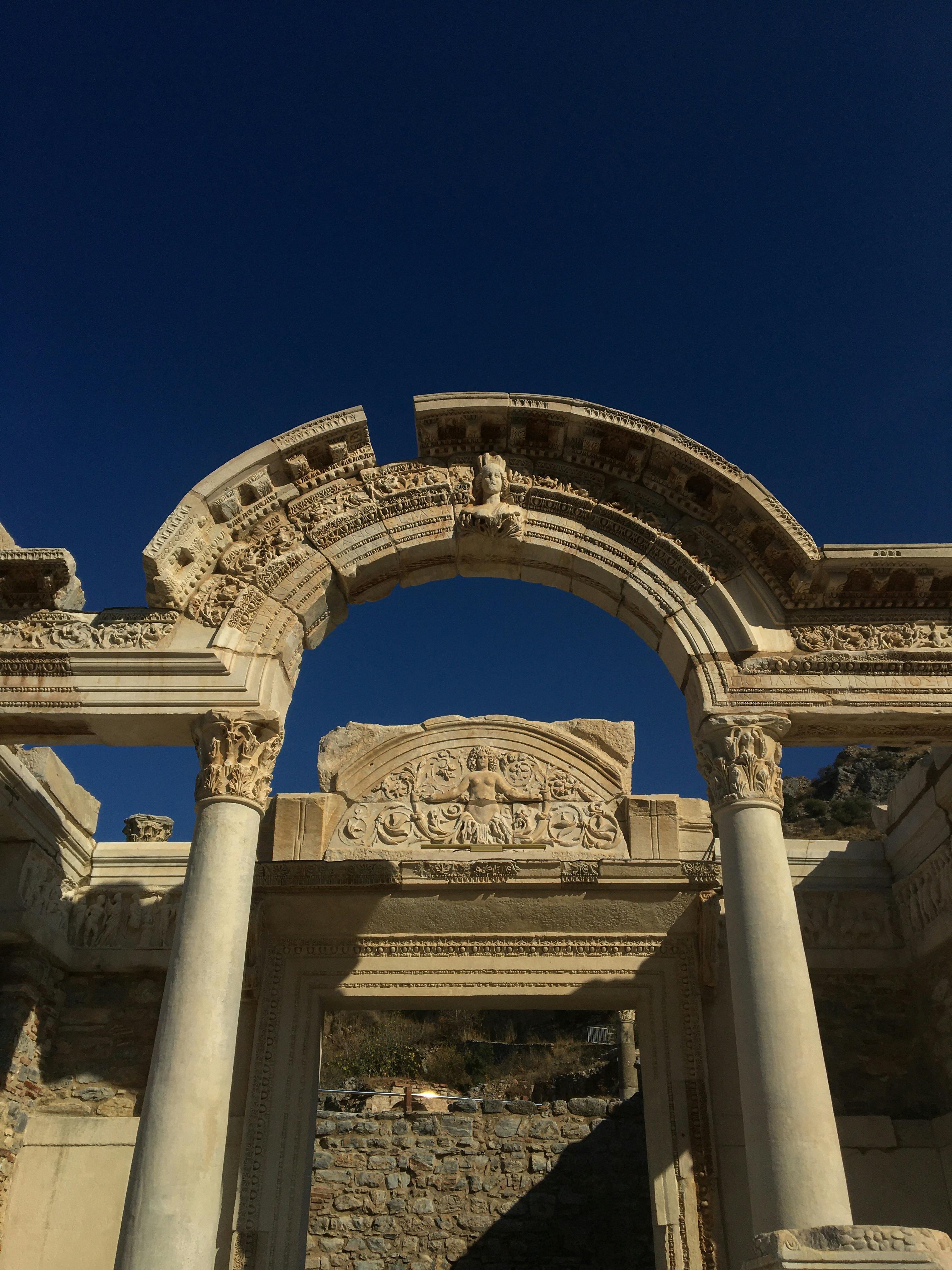 Discover the stunning architecture of ancient Roman ruins with ornate arches under a clear blue sky.