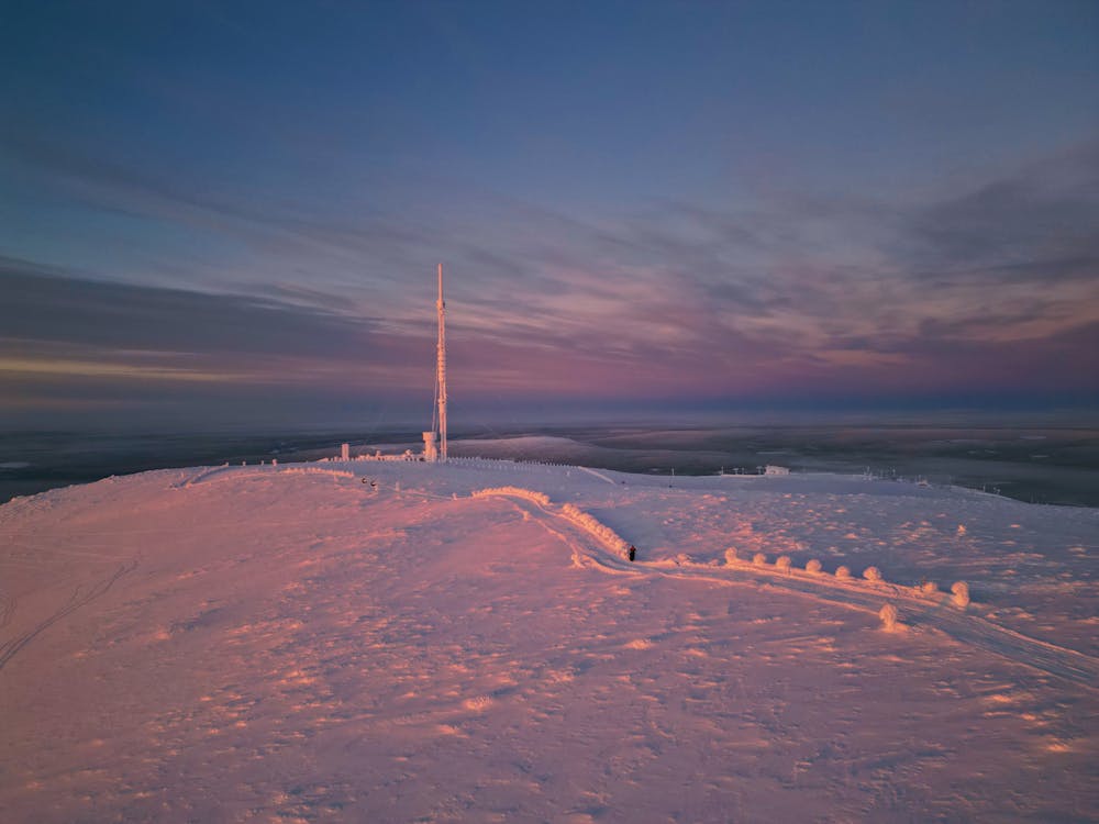 A snow covered hill with a pole on top