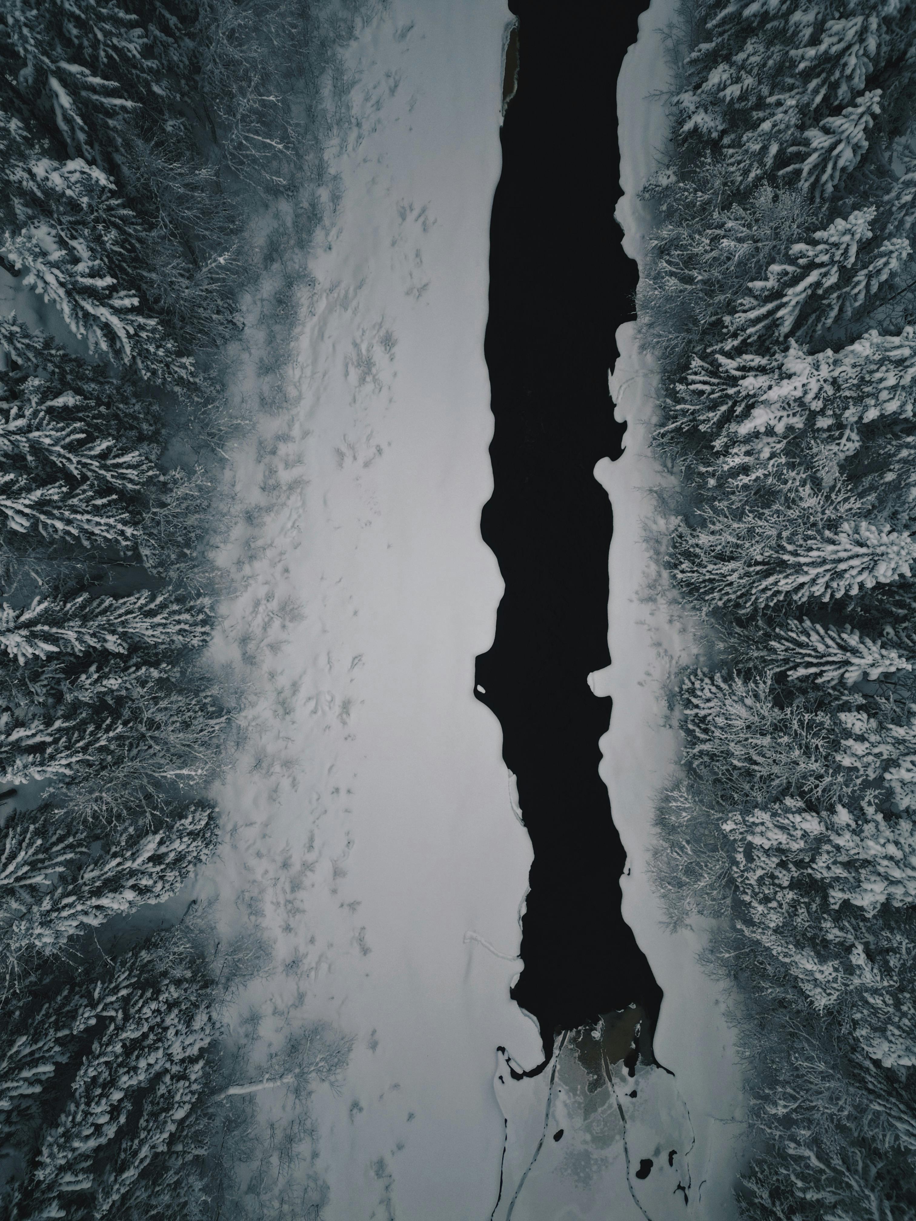 Stunning aerial view of a frozen river cutting through a winter forest in Finland.