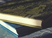 特写镜头捕捉到两本精装书堆叠在图案表面，展现出复杂的封面细节