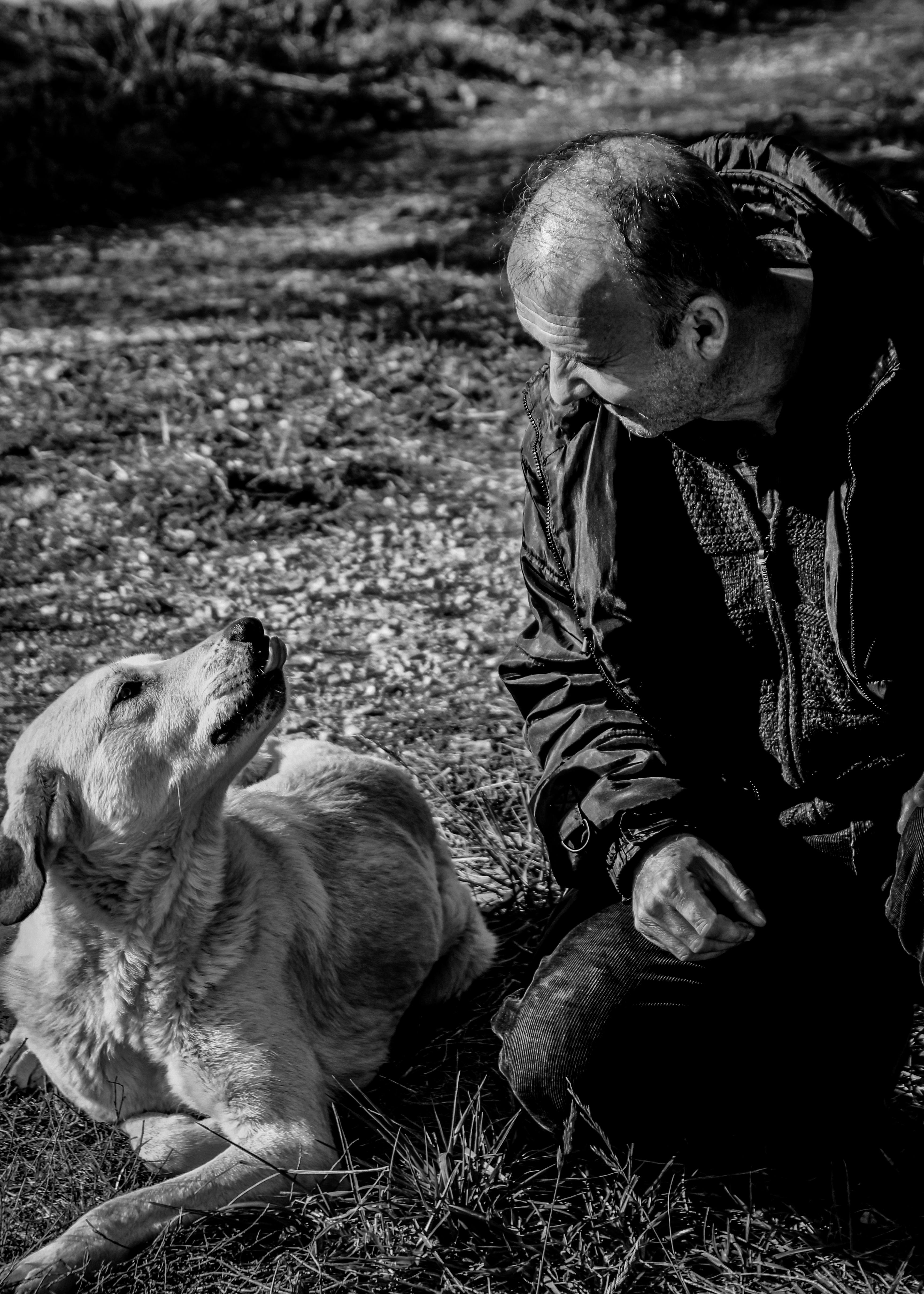 A man and his dog engage in a heartfelt moment, captured in black and white.
