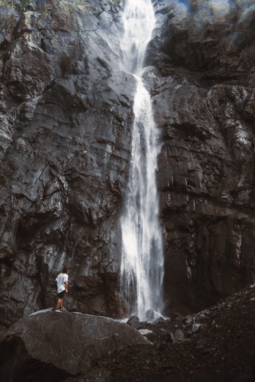 Man on Rocks under Waterfall