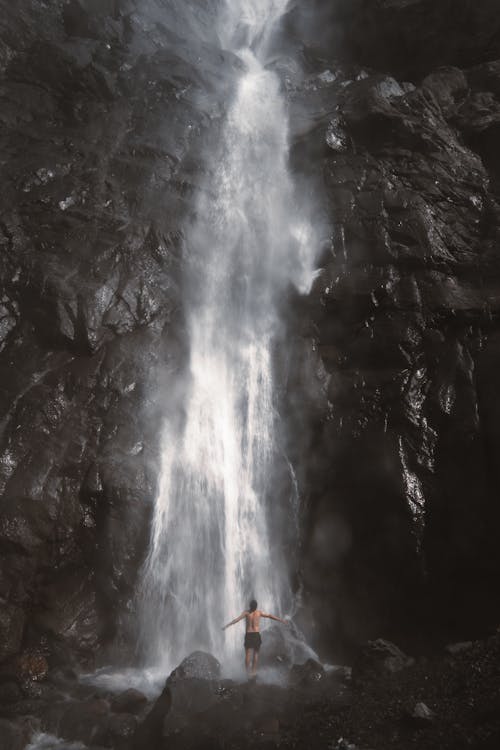 Man Standing under Waterfall