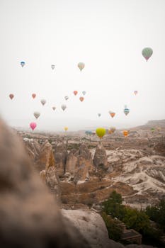 Scenic view of colorful hot air balloons soaring over Cappadocia's unique rock formations in Turkey.