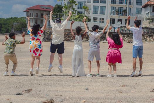 Joyful group of friends jumping together on a sandy beach.