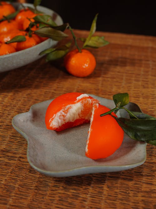 A plate with an orange on it and a leaf
