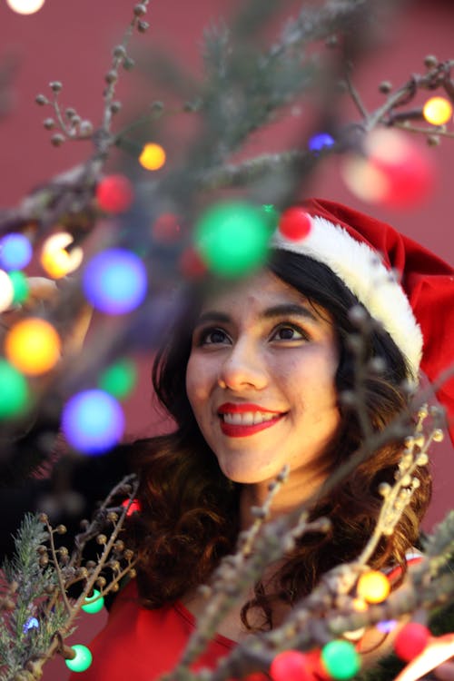 Smiling Brunette in Santa Hat by Christmas Tree