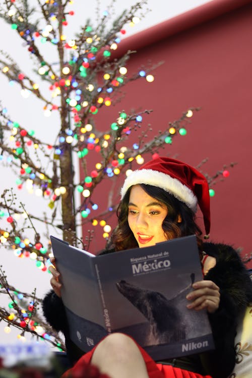 Woman Sitting and Reading Book in Santa Hat