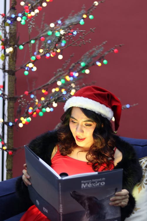 Young Brunette Reading Book by Christmas Tree