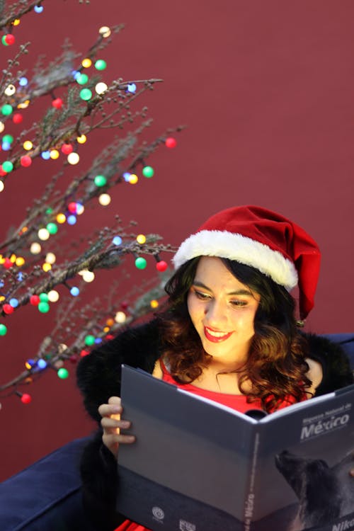 Smiling Woman in Santa Hat Reading Book