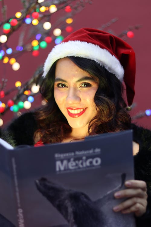 Smiling Woman in Santa Hat and with Book
