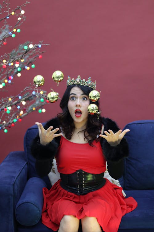 Woman in Crown Sitting and Throwing Christmas Balls