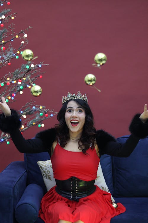 Smiling Woman Sitting in Crown and Throwing Christmas Balls